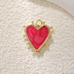 Detail showing a red heart pendant with a gold-beaded border and polished finish
