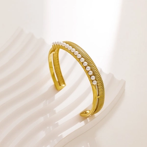 Detailed view of gold stainless steel open bangle with herringbone texture and pearls
