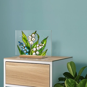 Detail of floral acrylic plaque with lily of the valley and wooden base on a sideboard
