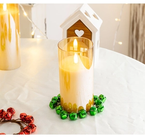 Detail of flameless LED candle with amber glass cover and green festive bell wreath