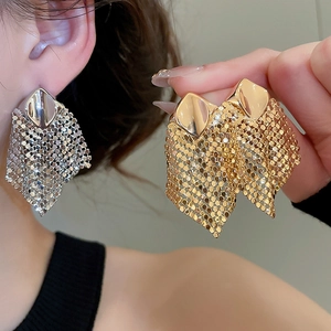 Detailed close-up of large metallic mesh tassel earrings in gold and silver finishes