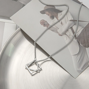 Detail view of silver snake chain with double triangle pendant on a metal plate
