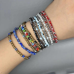 Stacked evil eye bead bracelets set in gold and blue tones on a model arm