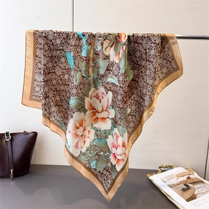 Dettaglio di sciarpa in seta con stampa floreale e bordo marrone dorato, drappeggio fine