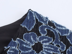 Détail de la broderie florale en denim bleu sur dentelle noire avec textures effilochées