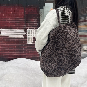Side view of large leopard print tote bag worn over shoulder on a suede strap
