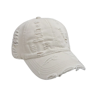 Close-up of distressed ripped details on off-white vintage washed cotton baseball cap