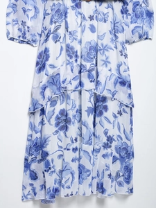 Détail d'une robe en mousseline fleurie bleue et blanche avec ourlet volanté et ceinture