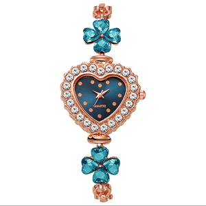 Macro view of heart-shaped rose gold watch dial with crystal bezel and clover details