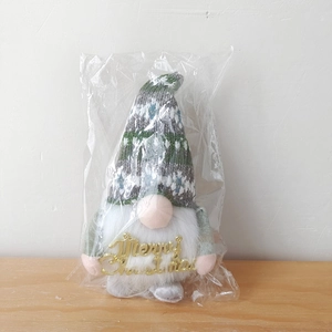 Detailansicht eines Weihnachtswichtels mit Merry Christmas Schild in Klarsichtverpackung