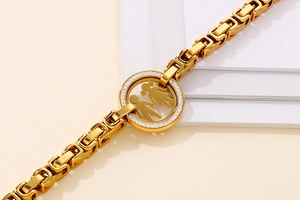 Macro shot of gold bracelet with a round charm featuring boy and girl silhouettes and diamonds