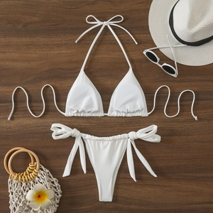 Flat lay di bikini a triangolo bianco con lacci laterali su sfondo in legno scuro