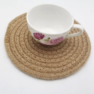 Detail of round braided jute coaster showing spiral natural wood color texture and thickness