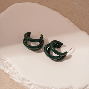 Détail de boucles d'oreilles en C à triple couche vert foncé sur pierre et sable