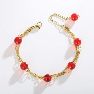 Detail of gold double-layer snake chain bracelet featuring translucent red round beads