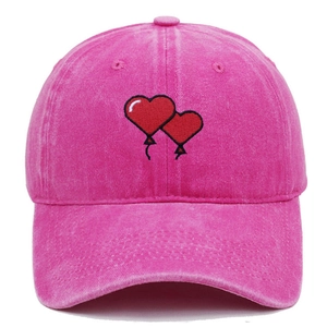 Pink washed cotton baseball cap with red heart embroidery on a white background