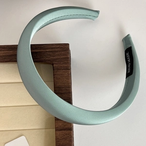 Detail of light green satin padded headband with silk sheen and handmade label