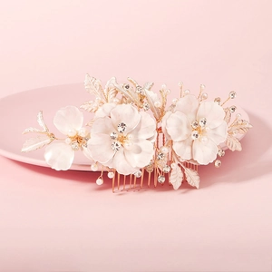 Detailed macro of golden bridal hair comb with enamel flowers, pearls, and rhinestones