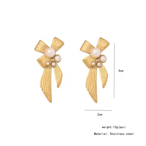 Detailed view of gold bow earrings with white pearls and 4cm length measurement