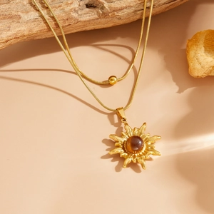 Détail du collier double rang doré avec pendentif soleil serti d'une pierre brune