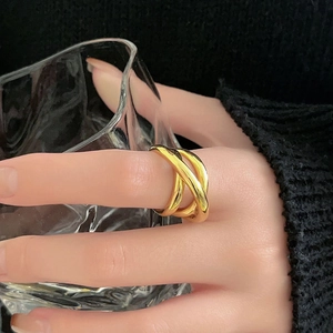 Close-up of triple layered gold braided open ring worn on finger with high gloss finish