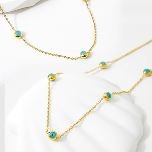 Golden stainless steel necklace featuring multiple blue evil eye beads on white shells