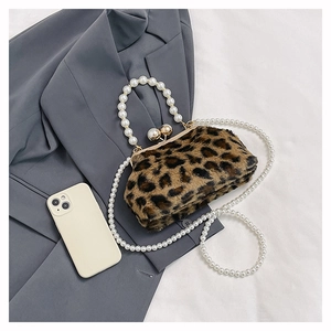 Close-up of leopard print plush handbag featuring elegant pearl handle and gold clasp