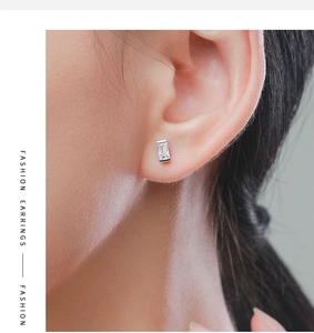 Close-up of a square zircon stud earring in s925 silver worn on a woman's ear
