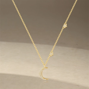 Detailed view of a gold crescent moon and stars pendant set with sparkling zircons