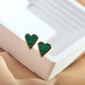 Macro shot of heart-shaped gold earrings with green striped malachite texture inlay