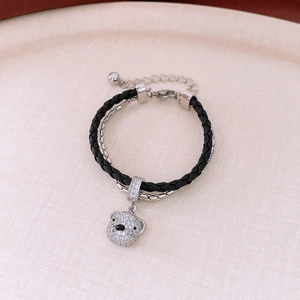 Detail of double-layer bracelet with crystal bear pendant and black braided rope
