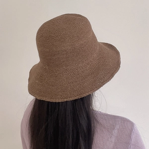 Macro detail of the hand-crocheted caramel straw hat showing tight weave and premium texture