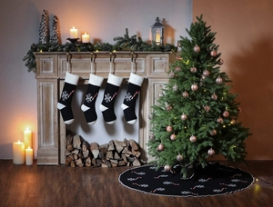 Detail of black knit Christmas stockings and tree skirt with snowflake and candy cane patterns