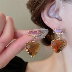 Detail of pink crystal and amber heart drop earring worn elegantly on the ear