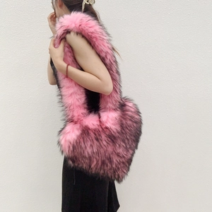 Detail shot of large pink heart-shaped faux fur bag shown on shoulder for size reference