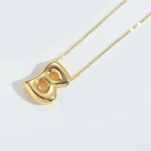 Macro shot of mirror-polished gold balloon letter 8 pendant on a fine necklace chain