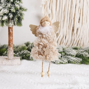 Ange de Noël en peluche avec ailes dorées suspendu à un sapin de Noël enneigé