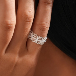 Detail of silver lace cutout ring with zircon oval floral pattern on finger