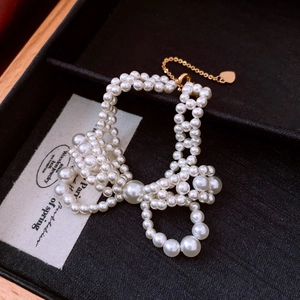 Detail of beaded pearl bow bracelet with a gold heart pendant and metallic chain