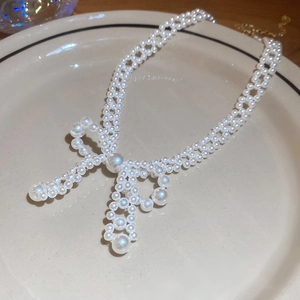 Détail du collier de perles avec nœud tressé sur une élégante assiette en céramique