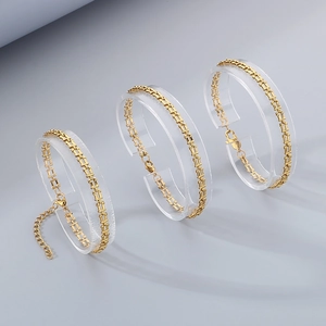 Detail of 18k gold plated stainless steel U-link chain bracelets on transparent stands