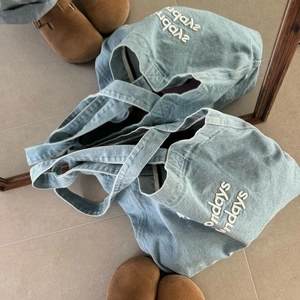 Close-up of light blue denim tote bag featuring white embroidered Sundays lettering