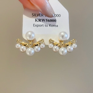 Detail of fan-shaped gold pearl earrings featuring five small pearls and sparkling rhinestones