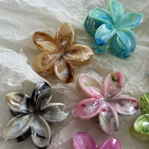 Macro detail of multi-colored marble pattern flower hair claws on white textured background