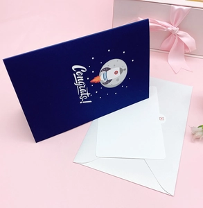 Detail view of deep blue greeting card set with rocket print, white envelope and small card