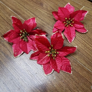 Detail of red poinsettia flowers with golden glitter edges on dark wood background