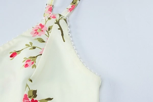 Detail of floral printed dress featuring pink roses and white lace trim on neckline