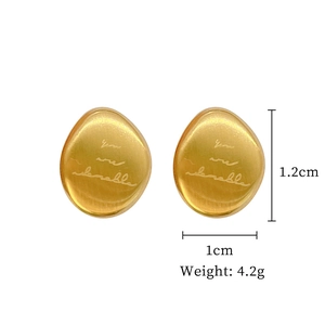Detail of egg-shaped gold titanium earrings engraved with 'You are adorable' text