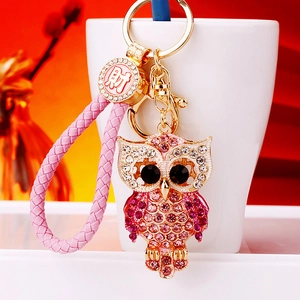 Detail of owl keychain with pink rhinestones, braided leather strap and gold metal charms