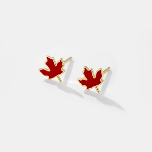 Macro shot of red maple leaf stud earrings with gold trim on a white background